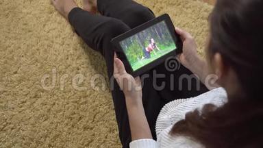 女孩在地毯上坐在家中用平板电脑屏幕观看<strong>体育训练</strong>视频